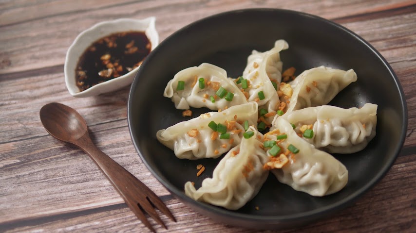 A plate of dumplings with dipping sauce